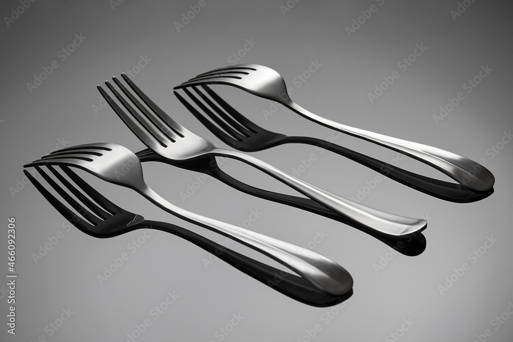 The forks lies on a gray glossy background. The middle fork lies with