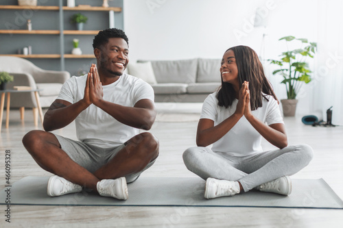 Black couple meditating keeping hands together in prayer pose