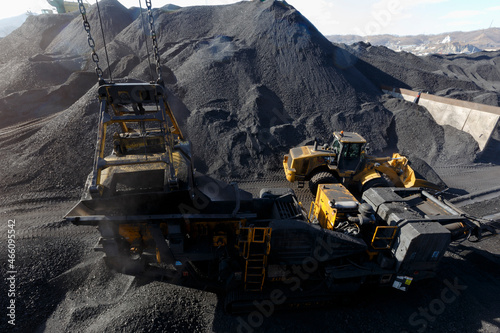 Extraction and processing of coal. A bulldozer transfers coal onto a conveyor belt. photo