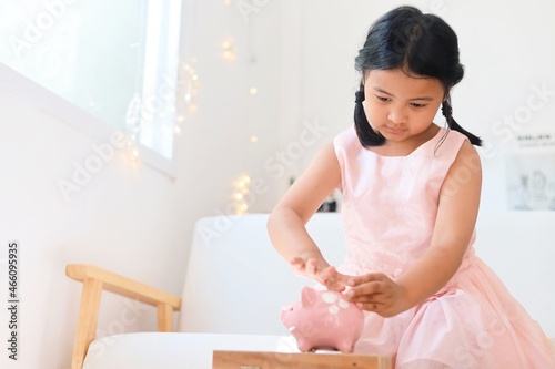 girl putting bank notes in piggy bank.