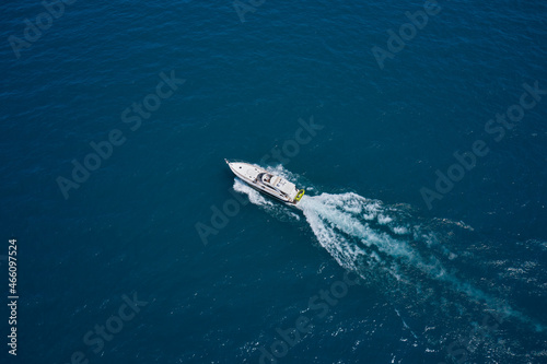 Large white yacht on the water in motion top view. Luxury motor boat on dark blue water aerial view. Travel on high-speed boats on the water. The yacht is fast moving on dark water. © Berg