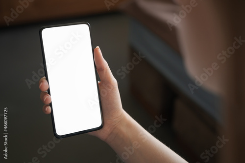 Young woman hold smartphone with white screen while sitting on a couch