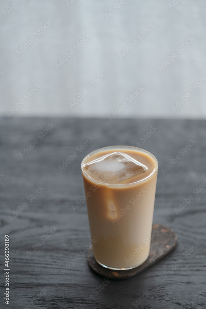 Ice coffee wih milk in tumbler glass on black oak table Ice coffee wih milk in tumbler glass on black oak table