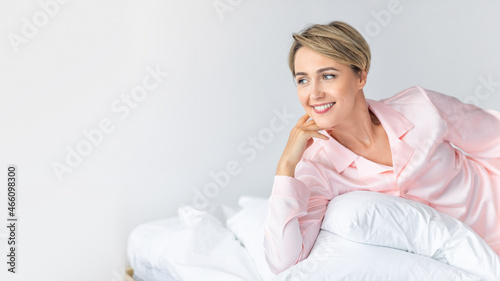 Happy woman looking away and thinking in bed