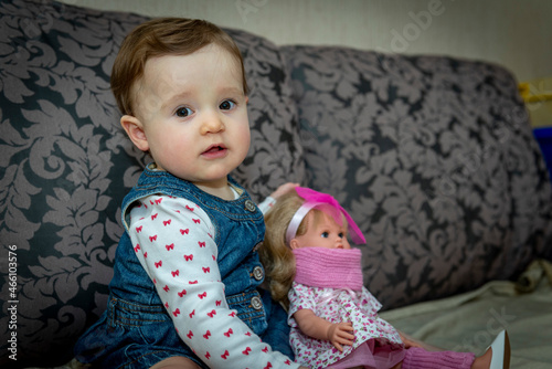 little baby girl with doll on the couch