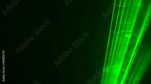 Colorful green neon laser lights on black studio background spinning in puffs of smoke. Laser holograms turns and emits light beams. Light effects for design, stage lighting, show, disco. Close up. photo