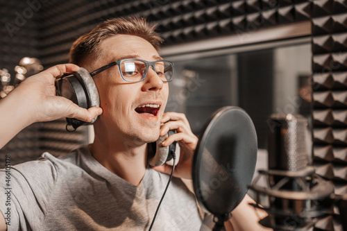 The vocalist sings in the studio in a microphone. Man in headphones writes a podcast, an audiobook. Artist, recording an album, working with the label. Announcer records a speech at a radio station