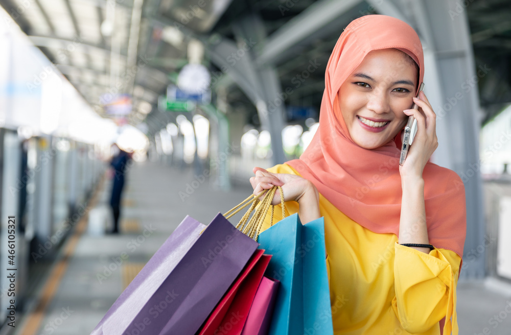 Arabic women shopping outdoors Girls with traditional arabian dress.Modern Lifestyle of Arab Muslim young woman in veil hijab with shopping bags walking on the shopping street phone calling. Arabic women shopping outdoors Girls with traditional arabian dress.Modern Lifestyle of Arab Muslim young woman in veil hijab with shopping bags walking on the shopping street phone calling.