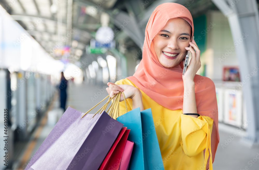 Arabic women shopping outdoors Girls with traditional arabian dress.Modern Lifestyle of Arab Muslim young woman in veil hijab with shopping bags walking on the shopping street phone calling. Arabic women shopping outdoors Girls with traditional arabian dress.Modern Lifestyle of Arab Muslim young woman in veil hijab with shopping bags walking on the shopping street phone calling.