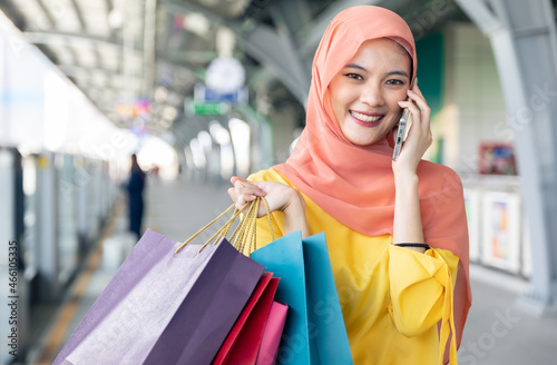 Arabic women shopping outdoors Girls with traditional arabian dress.Modern Lifestyle of Arab Muslim young woman in veil hijab with shopping bags walking on the shopping street phone calling.