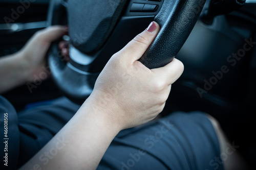 Young woman holding steering wheel with hands while driving a car