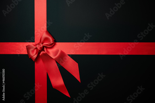Red gift ribbon bow on black background. Table top view, flat lay, copy space.