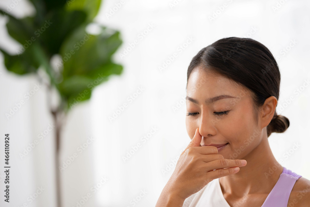 To guide her breath, an Asian lady touches her nostrils with her fingers. To get started with yoga and meditation To guide her breath, an Asian lady touches her nostrils with her fingers. To get started with yoga and meditation