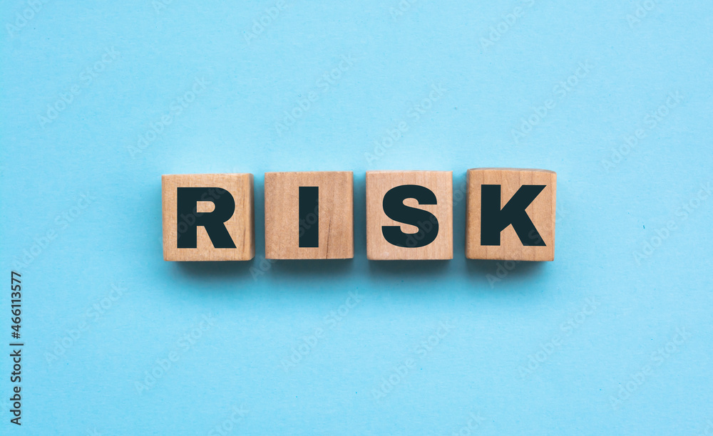 Word Risk made of small wooden cubes on blue background Word Risk made of small wooden cubes on blue background