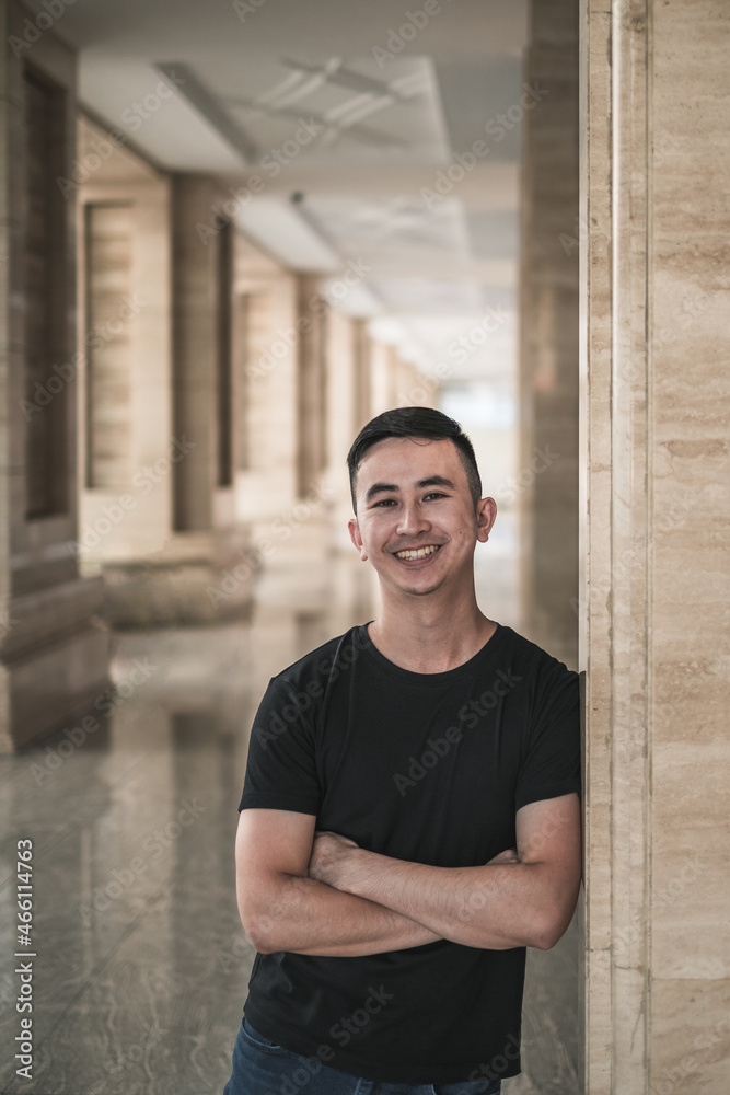 Obraz premium Portrait of asian young handsome man in casual clothing standing outdoors and smiling. Chinese people, real life, looking at camera with copy space
