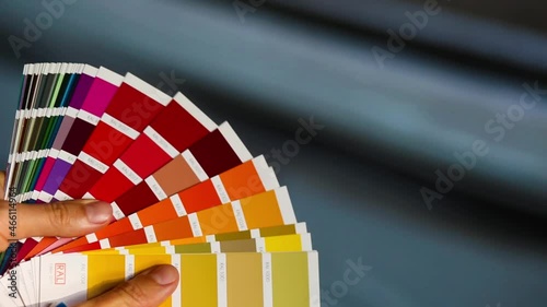 Selection of the paint color for decorative home repairs to the palette with layouts of the RAL. A fan of shades in your hand inside the home. Repair and construction, paint and varnish coating photo
