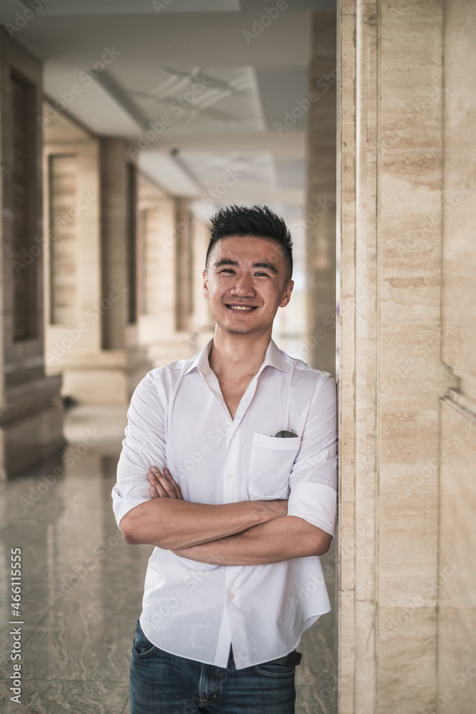 Obraz premium Portrait of asian young handsome man in casual clothing standing outdoors and smiling. Chinese people, real life, looking at camera with copy space