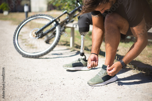 Close-up of person with disability tying laces. Man with mechanical leg getting ready for riding bicycle. Sport, disability concept
