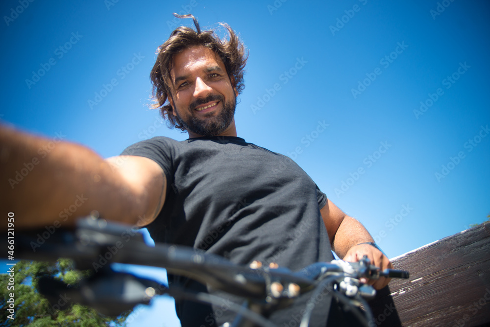 Handsome man taking selfie in park. Person in black t-shirt with bicycle picturing himself in park. Sport, disability concept