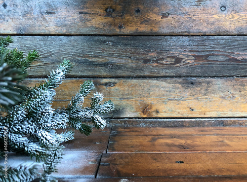 Snow-covered fir branches on a background of wooden boards.