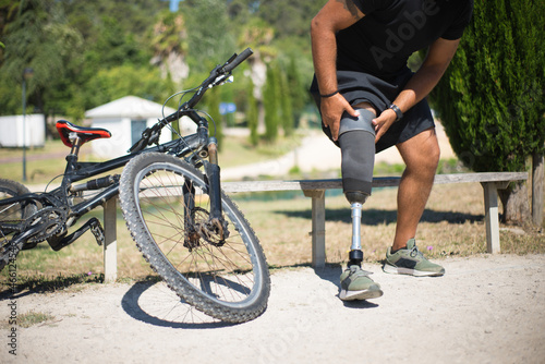 Close-up of person with disability getting ready for training. Man adjusting mechanical leg. Sport, disability concept