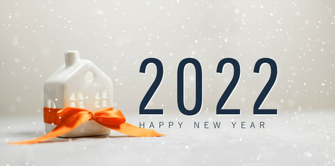 2022 Merry christmas and happy new year horizontal banner with small toy model house wrapped in red satin ribbon on beautiful white background