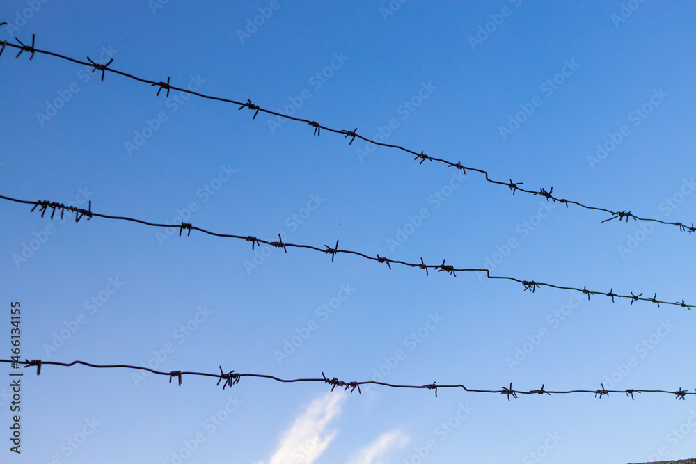 Barbed wire fence against blue sky. Dangerous area. Barbed wire fence against blue sky. Dangerous area.