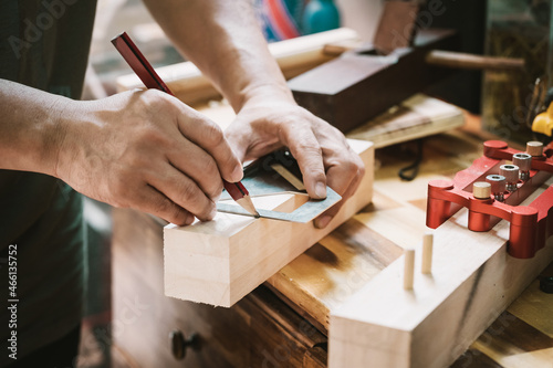 carpenter using a red pencil to draw a line on wood at workshop.,DIY maker and woodworking concept. selective focus