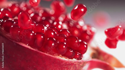 Pomegranate Grains rolls down on surface of broken pomegranate in slow motion