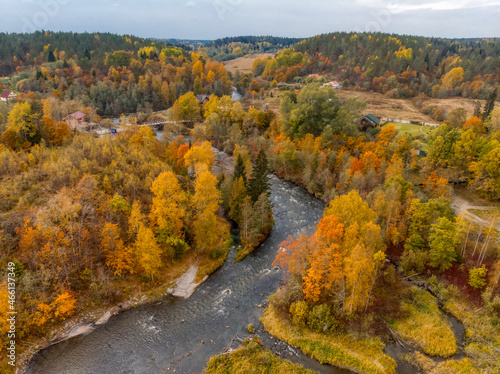 Aerial view on the mountain river and various trees with orange, yellow and green leaves. Cloudy sky. Karelian nature, Russia. Autumn season. Photo from the drone. Autumnal landscape.