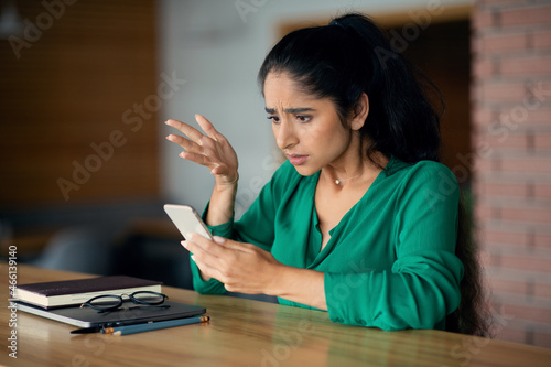 Emotional muslim lady using cellphone while working at cafe