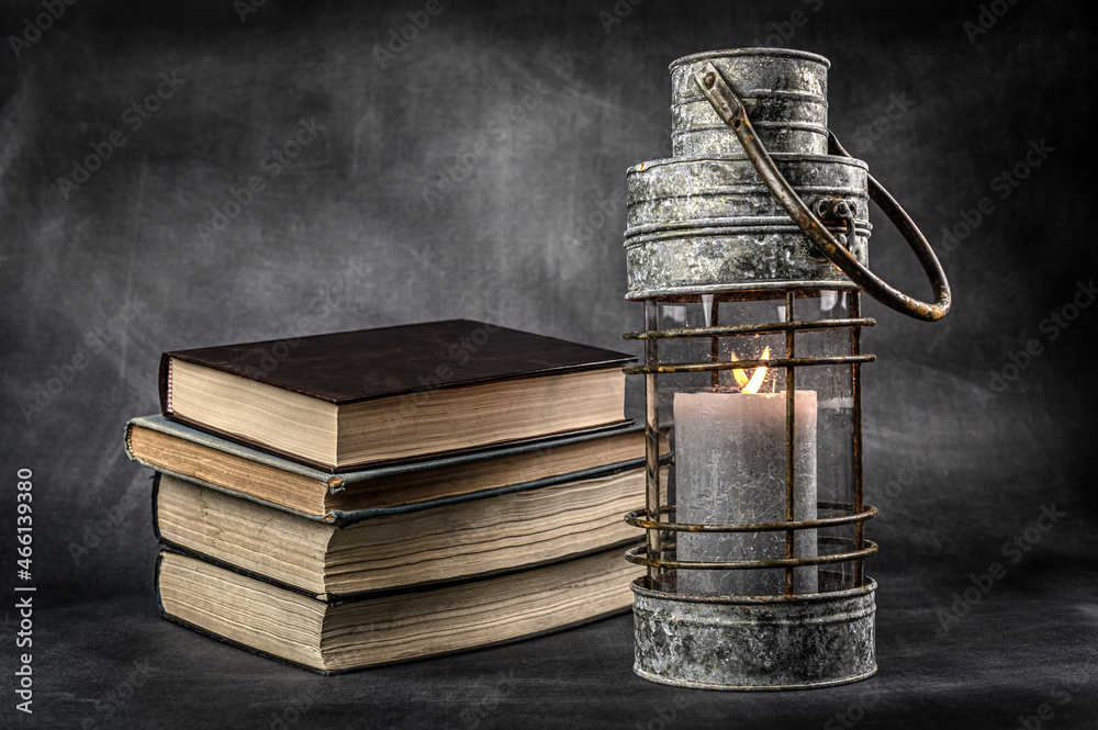 stos książek i latarnia z płonącym ogniem jako symboliczna kompozycja martwej natury
