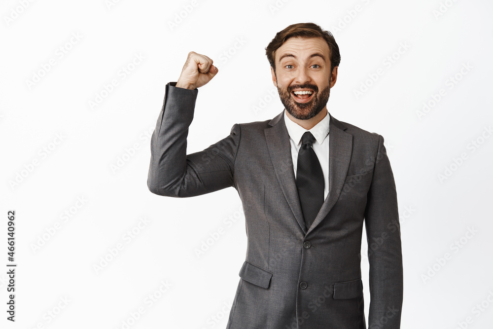 Cheerful businessman rooting for team, raising clench fist in support, smiling and looking hopeful at camera, encourage team, standing over white background Cheerful businessman rooting for team, raising clench fist in support, smiling and looking hopeful at camera, encourage team, standing over white background