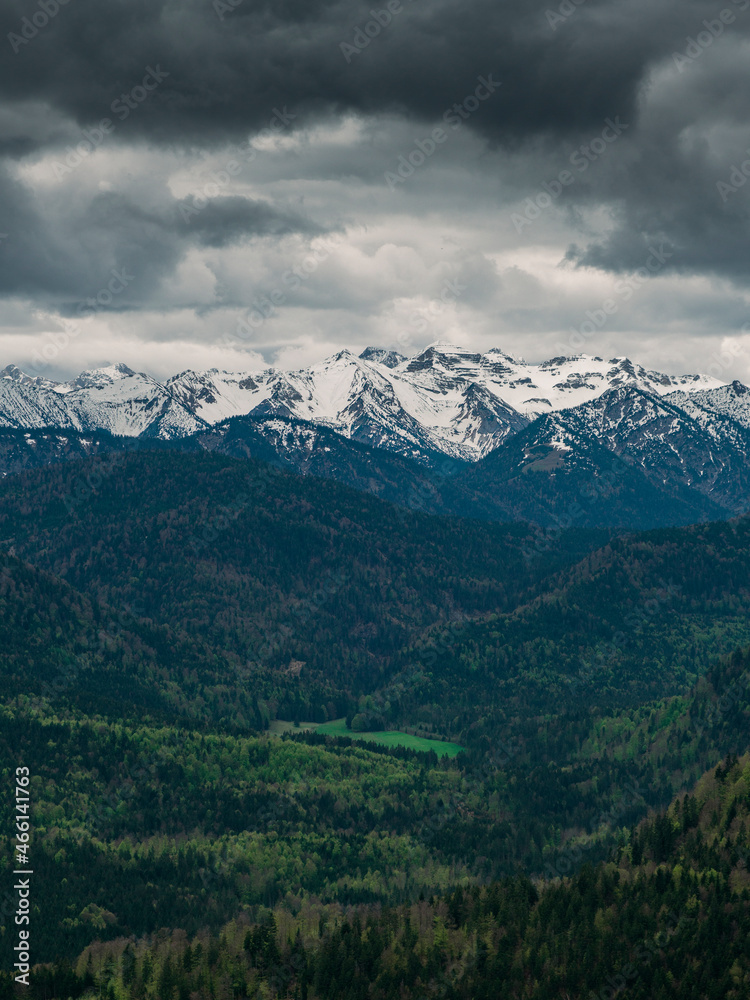 Fototapeta premium Snow covered Bavarian Alps with dramatic dark clouds, green forest at Jachenau near Lake Walchensee, Bavaria.