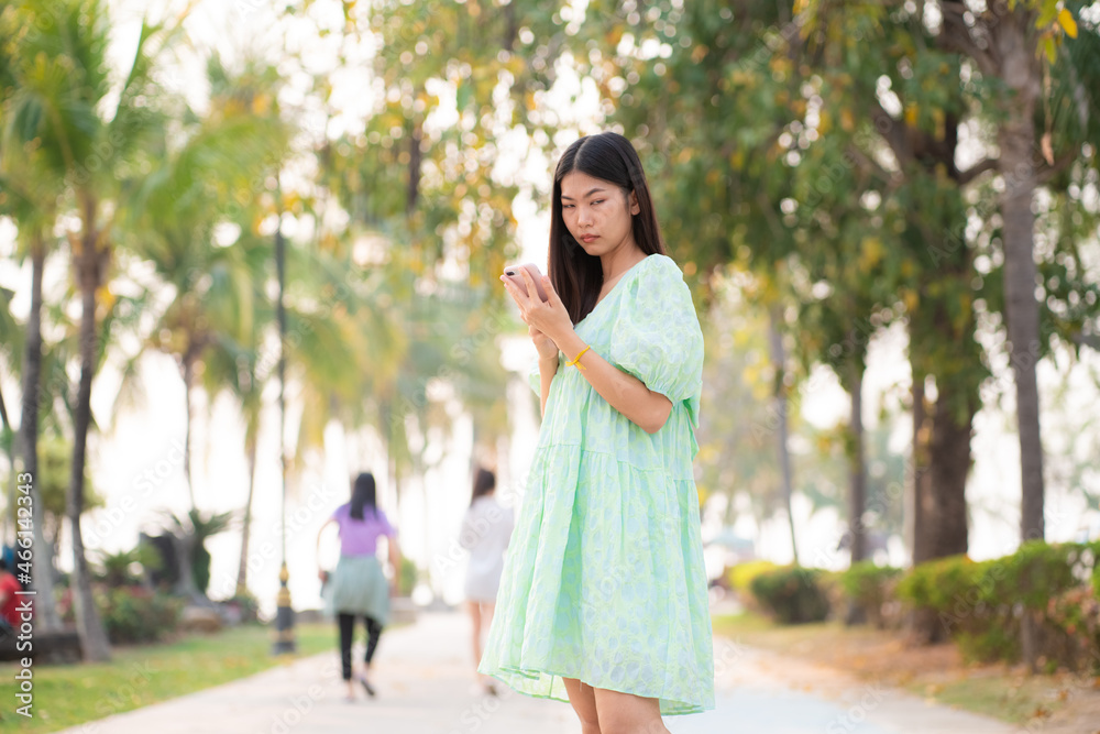 Beautiful asian women use cell phone outdoor park Beautiful asian women use cell phone outdoor park