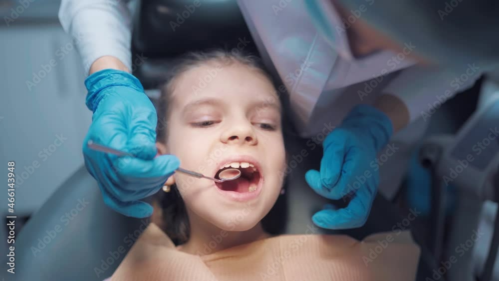 Close up face of little girl patient with open mouth during dental checkup teeth condition use tools Close up face of little girl patient with open mouth during dental checkup teeth condition use tools