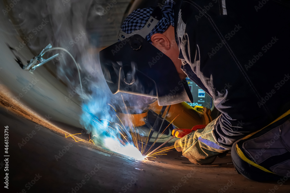 MMA welding. A welder welds large diameter pipes with manual electric arc welding. MMA welding. A welder welds large diameter pipes with manual electric arc welding.