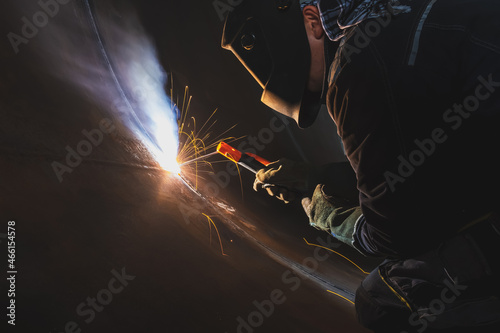 MMA welding. A welder welds large diameter pipes with manual electric arc welding.