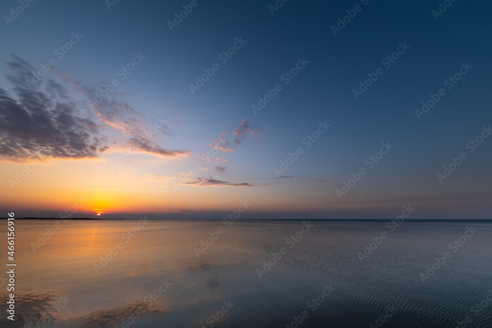Fototapeta premium Beautiful, colorful sunset, sunrise over a wide river. Twilight rays and clouds reflected in the calm water. 