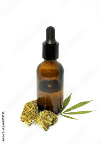 Bottle with CBD oil or tincture with marijuana leaf and buds on white background. CBD, a preparation for medical use extracted from cannabis.