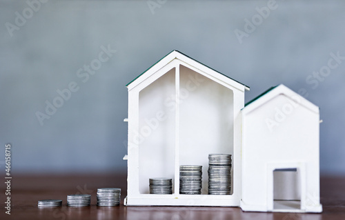 Miniature house models and construction truck models with coin on wooden table. Real estate development or property investment. Construction industry business concept. © Eve