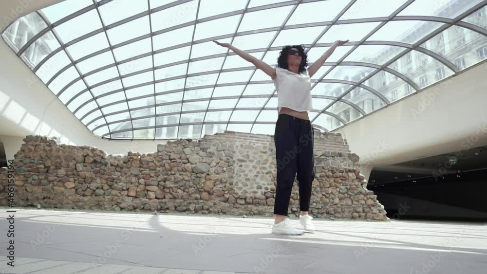 Happy beautiful hispanic woman walking and jumping at Serdica, Sofia with view of National Assembley at background, slow motion Happy beautiful hispanic woman walking and jumping at Serdica, Sofia with view of National Assembley at background, slow motion