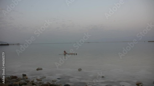 fat man swims in dead sea in the evening. low light soft focus