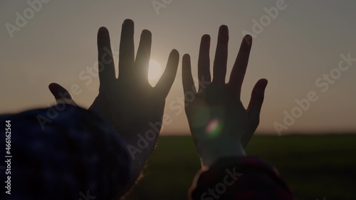 hands at sunset, lovers reach for the sky, dream of a good, good desire of people, ask for help from the sun, pray in the rays of sunlight, bright glare through the fingers of people's palms