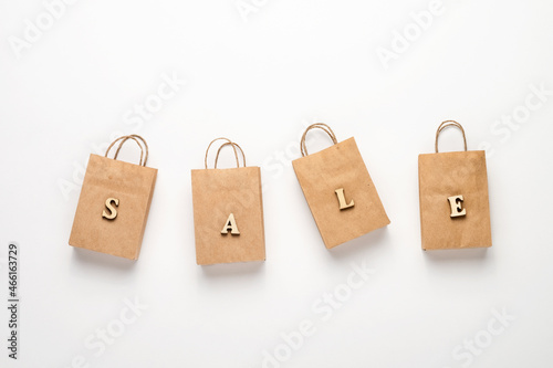 Paper shopping bags and the word sale on a white background. The concept of delivery of purchases and sales.