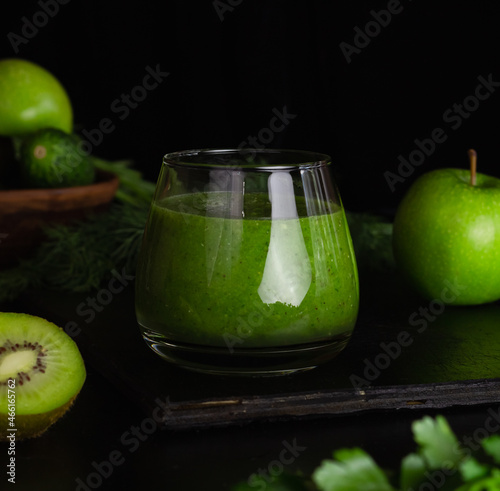 Green smoothie in a glass glass on a black background. Kiwi, apples,cucumbers and greens. Cooking healthy food.