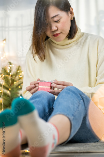 asian woman tieding ribbon and hold new year gift box and decorate christmas tree