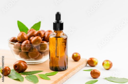 Jojoba oil in a bottle with a dropper on a wooden table with ripe jojoba fruits. Chinese Date Oil and Fruit photo