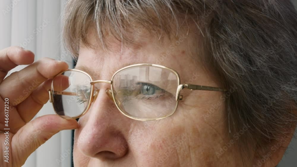 Close-up face of an elderly woman with blue eyes, glasses reflecting the city. The hair is gray and the face is marrowed and the skin is covered with age spots. Calm face of grandma Close-up face of an elderly woman with blue eyes, glasses reflecting the city. The hair is gray and the face is marrowed and the skin is covered with age spots. Calm face of grandma