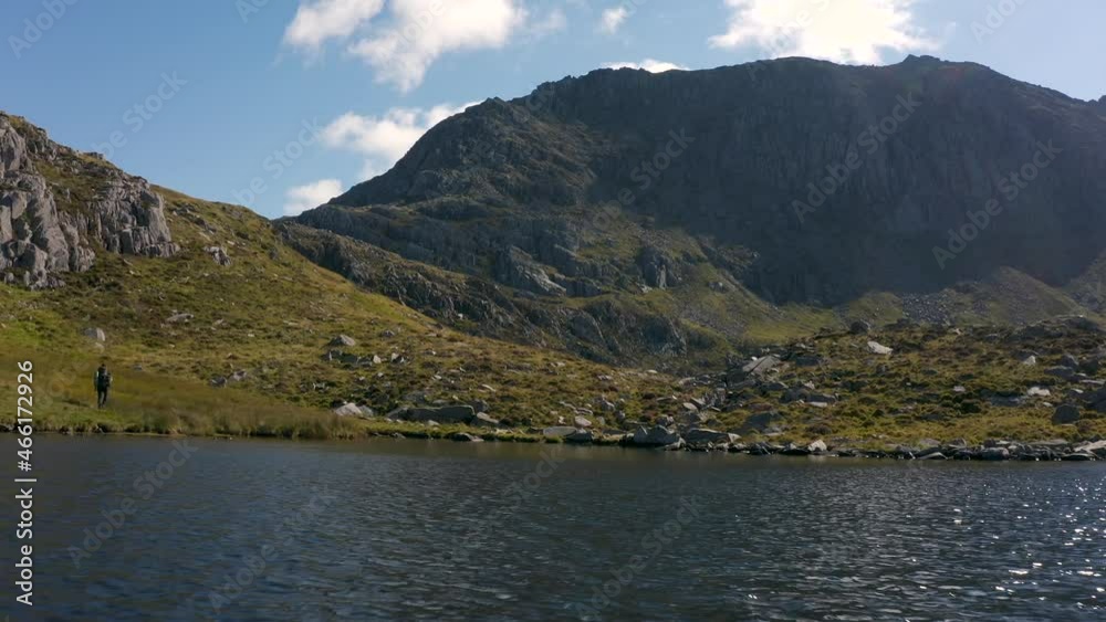 A man hiking beside a lake towards a mountain A man hiking beside a lake towards a mountain